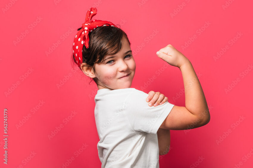 Cute powerful little girl showing muscles